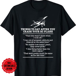 May include: A black t-shirt with a white graphic of a small airplane and text that reads "Things to say after you crash your RC plane". The text includes a list of humorous quotes about crashing an RC plane.