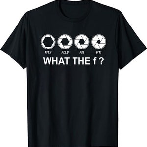Könnte beinhalten: Schwarzes T-Shirt mit einer weißen Grafik von vier Kamera-Blendenstufen, beschriftet mit F/1.4, F/2.8, F/8 und F/11. Der Text "WHAT THE f?" befindet sich unter der Grafik.
