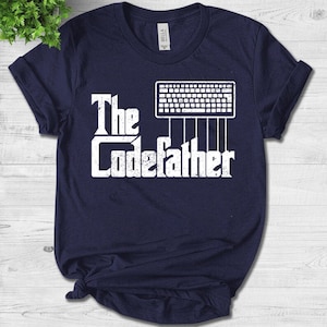 Op de afbeelding: Een marineblauw t-shirt met een witte afbeelding van een computertoetsenbord en de tekst "The CodeFather".