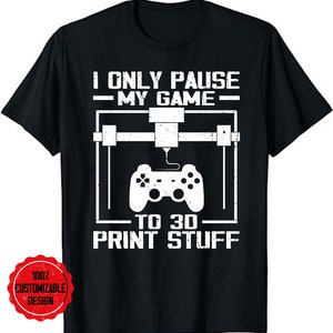 May include: Black t-shirt with white text that reads "I only pause my game to 3D print stuff". The text is surrounded by a graphic of a 3D printer and a video game controller.