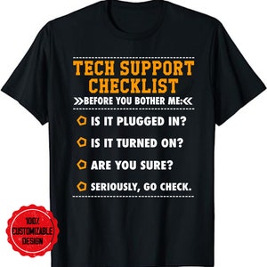 Op de afbeelding: Zwart T-shirt met een witte afbeelding met de tekst "Tech Support Checklist" met een lijst met vragen: "Is het aangesloten?", "Is het aan?", "Weet je het zeker?", "Echt waar, ga het controleren."