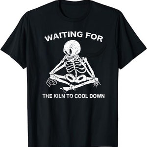 May include: Black t-shirt with a white skeleton sitting with its legs crossed and the text "Waiting for the kiln to cool down".
