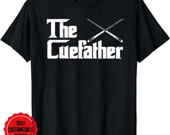Op de afbeelding: Zwart T-shirt met witte tekst "The Cuefather" en een afbeelding van twee gekruiste biljartstokken.