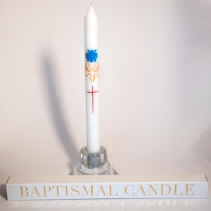 May include: White baptismal candle with a blue seashell, gold doves, and a red cross. The candle is on a clear glass base and the box reads "Baptismal Candle".