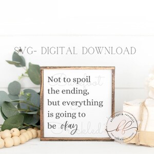 May include: A white wooden sign with a brown frame and the text "Not to spoil the ending, but everything is going to be okay" in black lettering. The sign is sitting on a white surface with a wooden bead garland and a bouquet of white flowers.