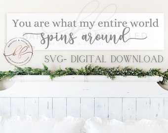 May include: A white wooden sign with gray text that reads "You are what my entire world spins around". The sign is sitting on a white headboard with a green garland above it. The sign is for sale as a digital download.