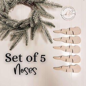 Op de afbeelding: Set van 5 houten wortelneuzen voor knutselen. De neuzen zijn lichtbruin en hebben een natuurlijke houten afwerking. De tekst "Set of 5 Noses" is in zwart op een witte achtergrond gedrukt.