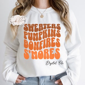 May include: White sweatshirt with a graphic design of the words "Sweaters, Pumpkins, Bonfires, S'mores" in a retro font with orange and brown colors. The text "Digital File" is also included on the sweatshirt.