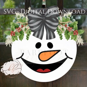 May include: A white snowman face with a black and white striped bow, red cheeks, a black nose, and an orange carrot nose. The snowman face is surrounded by green holly leaves with red berries.