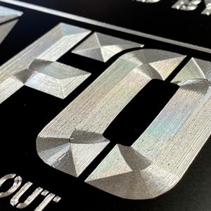 Pu&ograve; includere: Primo piano di un cartello metallico argentato con la parola "CRAFTED" in rilievo, in un carattere testurizzato, su sfondo nero. Il testo "Find out" &egrave; visibile sotto la parola "CRAFTED".