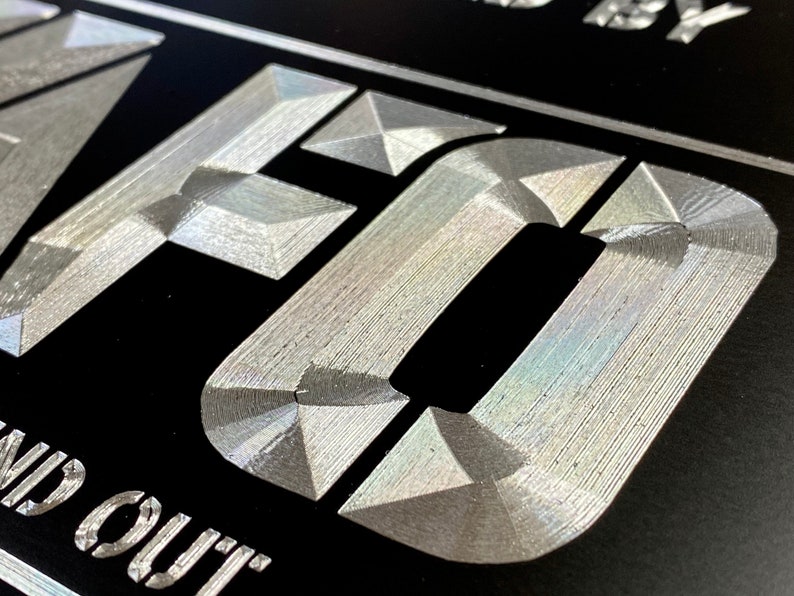 Pu&ograve; includere: Primo piano di un cartello metallico argentato con la parola "CRAFTED" in rilievo, in un carattere testurizzato, su sfondo nero. Il testo "Find out" &egrave; visibile sotto la parola "CRAFTED".