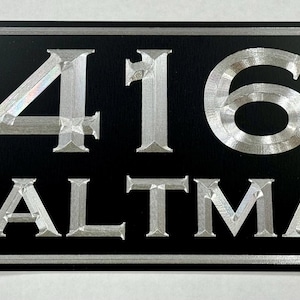May include: A black rectangular sign with silver lettering. The number 416 and the name "WALTMAN" are displayed on the sign.