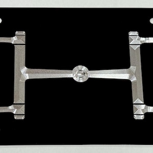 May include: A silver metal horse bit design on a black background. The bit is a traditional design with two rings and a center bar. The bit is a popular design for horse riders.