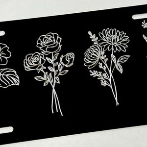 Peut inclure: Quatre motifs floraux diff&eacute;rents sont grav&eacute;s en blanc sur un fond noir. Les motifs comprennent un bouquet de roses, un bouquet de marguerites, un bouquet de gloire du matin et un bouquet de pens&eacute;es.