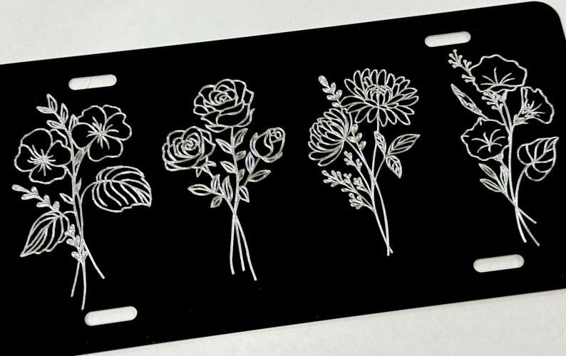 Peut inclure: Quatre motifs floraux diff&eacute;rents sont grav&eacute;s en blanc sur un fond noir. Les motifs comprennent un bouquet de roses, un bouquet de marguerites, un bouquet de gloire du matin et un bouquet de pens&eacute;es.