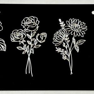 May include: Four different floral designs are etched in white on a black background. The designs include a bouquet of roses, a bouquet of daisies, a bouquet of morning glories, and a bouquet of pansies.