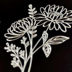 Peut inclure: Un motif floral argent&eacute; paillet&eacute; avec trois fleurs et des feuilles sur un fond noir.