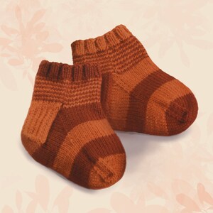 Può includere: Un paio di calzini per neonati in maglia a righe marroni e arancioni. I calzini sono realizzati in filato morbido e hanno una vestibilità comoda.