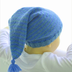 May include: A blue and light blue striped knitted hat with a long tassel. The hat has a pointed top and is worn by a child.