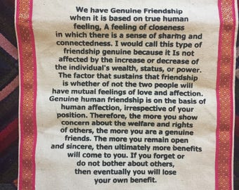 May include: A white canvas banner with a pink and gold border. The banner features a quote about friendship by the 14th Dalai Lama. The quote reads: "We have Genuine Friendship when it is based on true human feeling, A feeling of closeness in which there is a sense of sharing and connectedness. I would call this type of friendship genuine because it Is not affected by the increase or decrease of the individual's wealth, status, or power. The factor that sustains that friendship is whether of not the two people will have mutual feelings of love and affection. Genuine human friendship is on the basis of human affection, irrespective of your position. Therefore, the more you show concern about the welfare and rights of others, the more you are a genuine friends. The more you remain open and sincere, then ultimately more benefits will come to you. If you forget or do not bother about others, then eventually you will lose your own benefit. H.H. The 14th Dalai Lama"