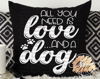 May include: A black decorative pillow with the text "All you need is love...and a dog" in white script. The pillow is flanked by two other pillows, one with a black and white geometric pattern and the other with a white mug.