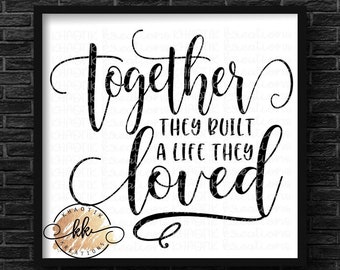 May include: Black and white typography print with the text "Together they built a life they loved". The print is framed in a black frame and has a gold logo in the bottom left corner.