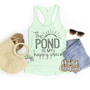 May include: A light green tank top with the text "The POND is my happy place" in black. The tank top is styled with a straw bag, sunglasses, and denim shorts.