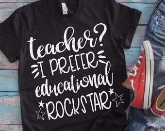 May include: Black t-shirt with white text that reads "teacher? I prefer educational rockstar" with a star on either side of the word "rockstar". The shirt is laid out on a blue and white wooden surface with a pair of blue jeans and red converse shoes.