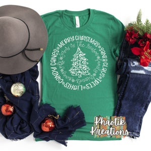 May include: Green t-shirt with a white circle design featuring a Christmas tree with a leopard print pattern. The text around the tree reads "Lights*Trees*Wreaths*Presents*Santa Claus*Ribbon*The reason is Jesus*Merry Christmas*Cans*Candy".