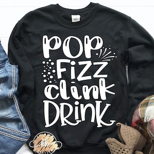 May include: Black sweatshirt with white text that reads "Pop Fizz Clink Drink".