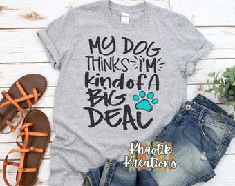 May include: Gray t-shirt with the text "My Dog Thinks I'm Kind of a Big Deal" in black with a turquoise paw print. The text is in a playful, handwritten font.