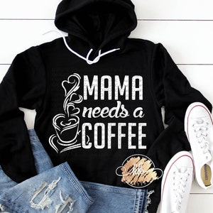 May include: Black hooded sweatshirt with white text that reads "Mama needs a coffee" and a stylized image of a coffee cup with steam rising from it.