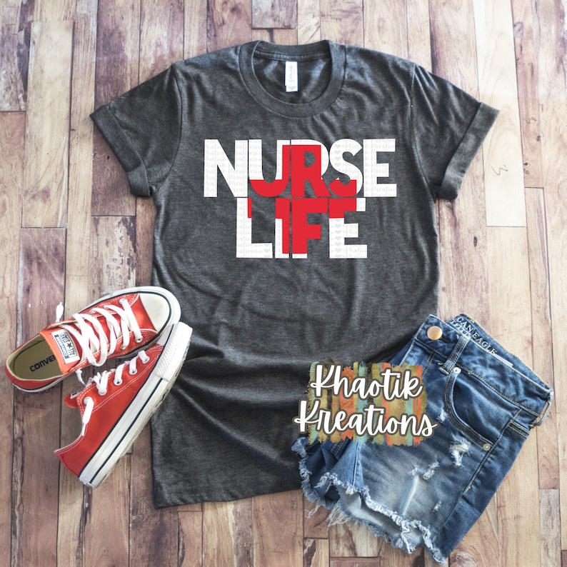 May include: A gray t-shirt with the words "NURSE LIFE" in white letters with a red cross in the middle of the word "LIFE".