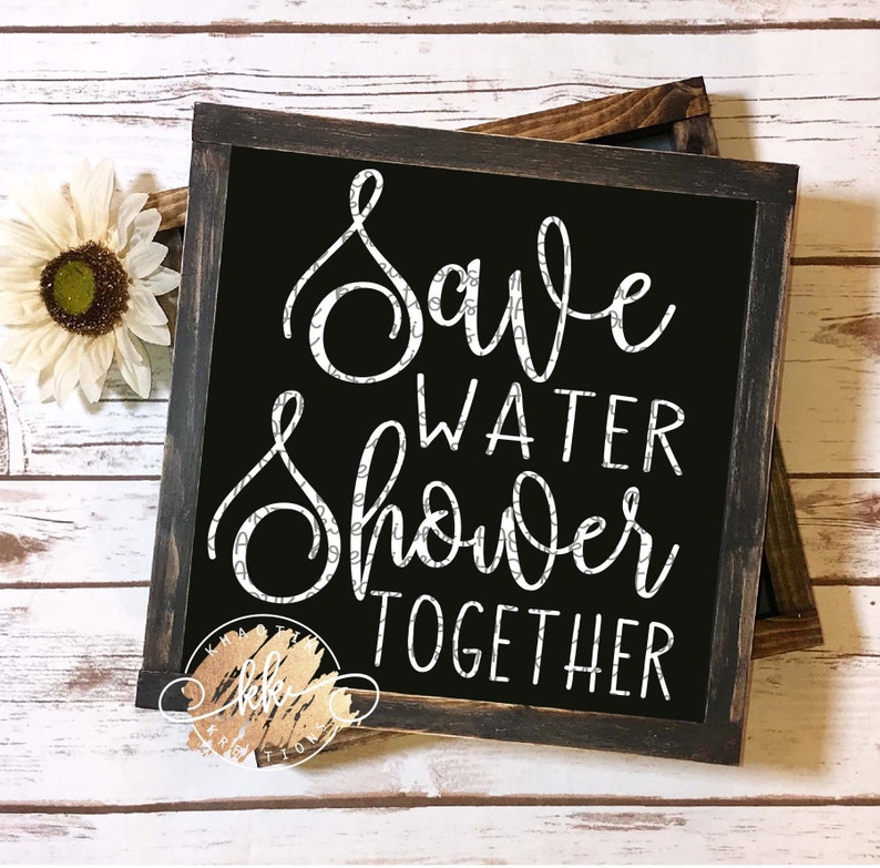 Puede incluir: Un letrero negro enmarcado con letras blancas que dice "Save Water Shower Together". El letrero est&aacute; sobre una superficie de madera blanca.