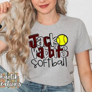 May include: A gray t-shirt with the text "Jack Rabbits Softball" in black and maroon lettering. A yellow softball with red stitching is included in the design.