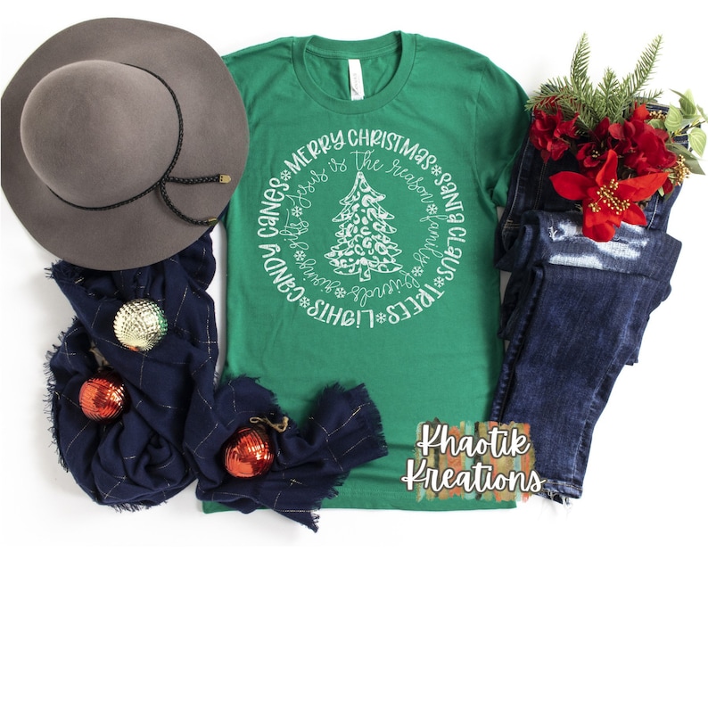 May include: Green t-shirt with a white circle design featuring a Christmas tree with a leopard print pattern. The text around the tree reads "Lights*Trees*Wreaths*Presents*Santa Claus*Ribbon*The reason is Jesus*Merry Christmas*Cans*Candy".