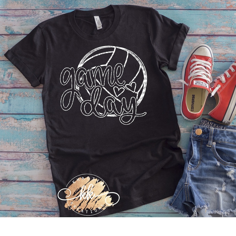 May include: Black t-shirt with a white volleyball graphic and the text "game day" in a distressed font. Two small hearts are above the word "day".