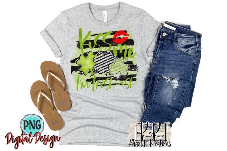 May include: A gray t-shirt with a black and white striped design and green shamrocks. The text "Kiss me I'm Irish-ish" is written in green. A red lip print is above the text.