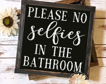 May include: A black framed sign with white text that reads "Please no selfies in the bathroom".