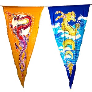 May include: Four triangular fabric pennants with dragon designs. The pennants are strung together and feature different coloured backgrounds and dragons. The first pennant is blue with a purple dragon, the second is yellow with a red dragon, the third is blue with a yellow dragon, and the fourth is green with a red dragon.