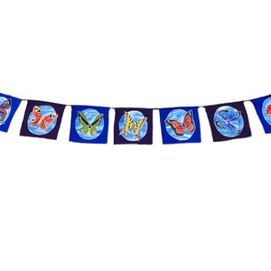 May include: A blue and white butterfly banner with eight flags. Each flag features a different colored butterfly on a blue circle.