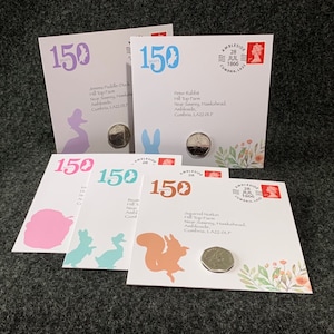 May include: Four white cards with colourful illustrations of animals from Beatrix Potter's children's books. Each card features a different animal: a duck, a rabbit, a squirrel, and a hedgehog. Each card has a silver coin on it and the text "150 years" and "Ambleside 28 Jul 1866 Cumbria, LA22 OLF".