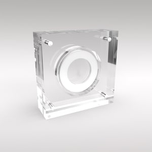 May include: A clear acrylic display case with a circular cutout for a coin or other small object. The case has four silver metal posts on the sides.