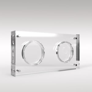 Puede incluir: Una vitrina de acrílico transparente con dos aberturas circulares. La caja rectangular tiene bordes redondeados y herrajes plateados. El diseño es minimalista y moderno, adecuado para exhibir objetos de colección o artículos pequeños.