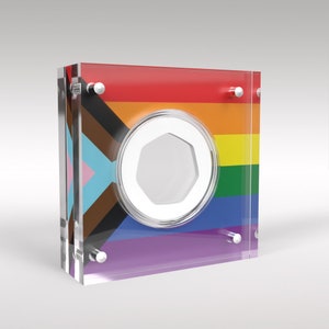 May include: A clear acrylic display case with a rainbow pride flag design. The case has a circular opening in the center, revealing a silver coin.