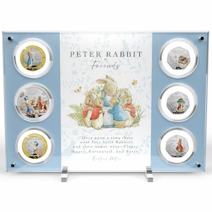 May include: A blue display case with six silver and gold coins featuring Peter Rabbit and his friends. The coins are arranged in a circle around a picture of Peter Rabbit and his friends. The quote "Once upon a time there were four little Rabbits, and their names were--Flopsy, Mopsy, Cottontail, and Peter." by Beatrix Potter is printed below the picture.