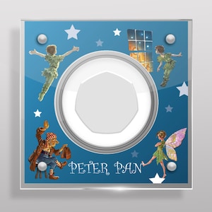 May include: A blue square glass light switch cover with a white circle in the center. The circle has a white octagon shape inside. The background has stars and images of Peter Pan characters. The text "PETER PAN" is printed below the circle.