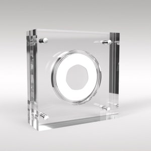 May include: A clear acrylic coin display case with a circular opening for a coin. The case has a modern design and is perfect for showcasing a valuable coin.
