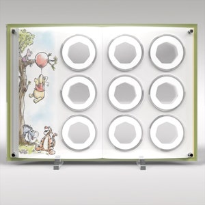 May include: A green and white book-shaped coin display case with a Winnie the Pooh illustration. The case has eight clear coin holders.