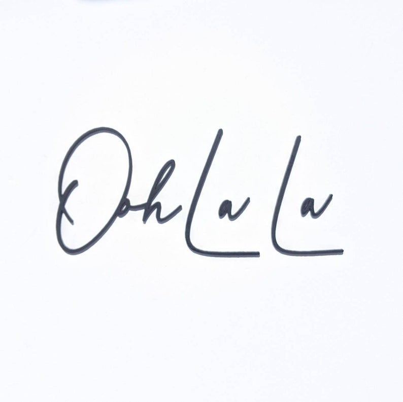 May include: Black and white cursive text that reads "Ooh La La" on a white background.